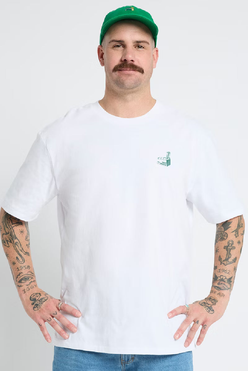 Man in a green cap wearing the Cricket Wickets lightweight white tee, front view with small chest print