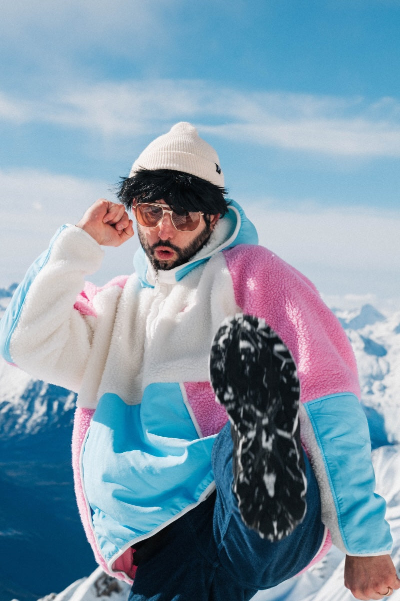 Person wearing a colorful jacket and sunglasses in a snowy landscape