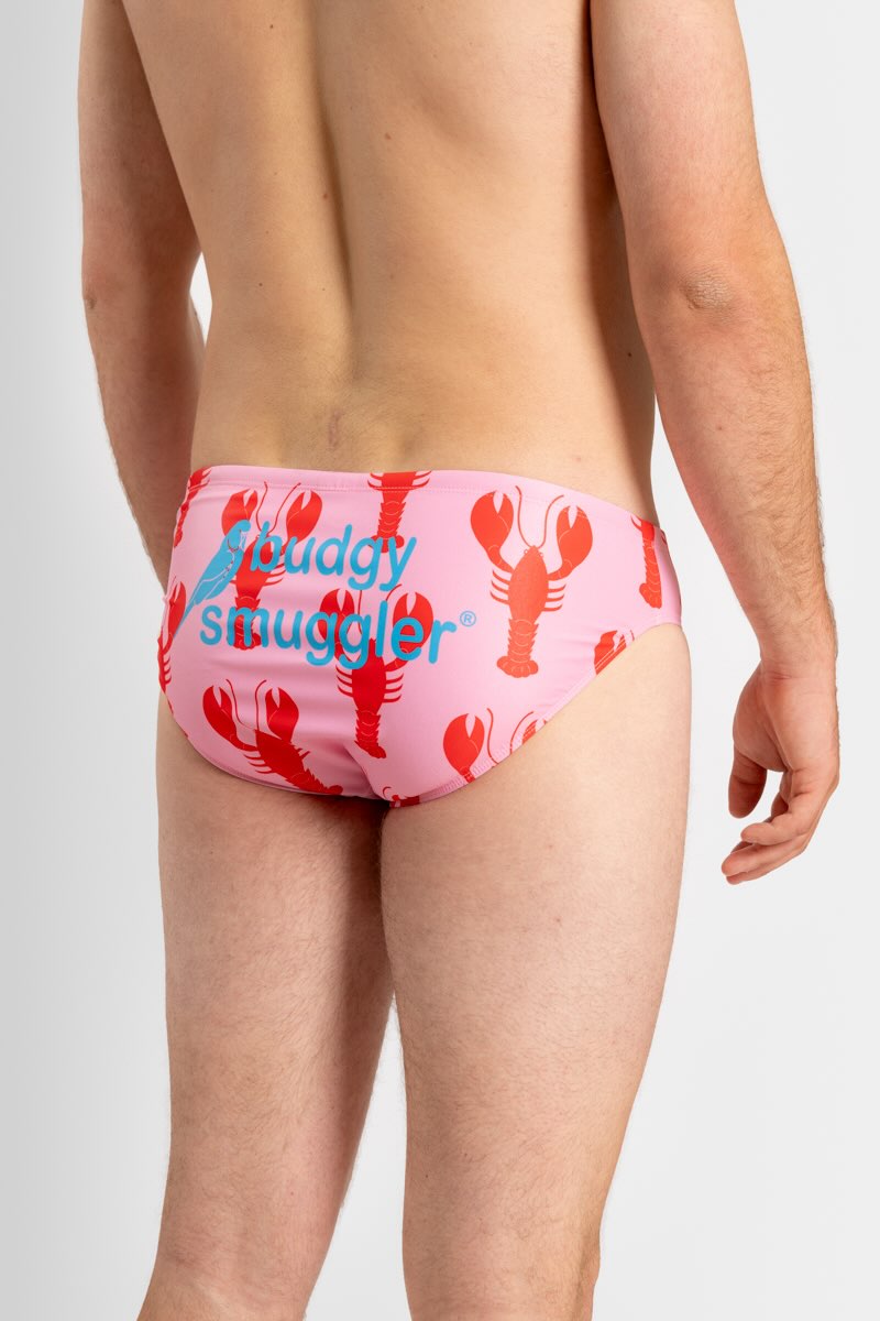 Pink swim briefs with red lobster design and 'Budgy Smuggler' text on a white background